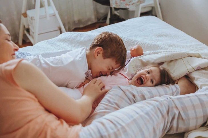 Closeup of happy family playing over the bed in a relaxed morning. Weekend family leisure time concept.