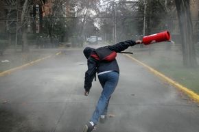 That student protester is actually throwing a regular fire extinguisher. That's not quite the same thing as one that's designed to be lobbed at a fire.